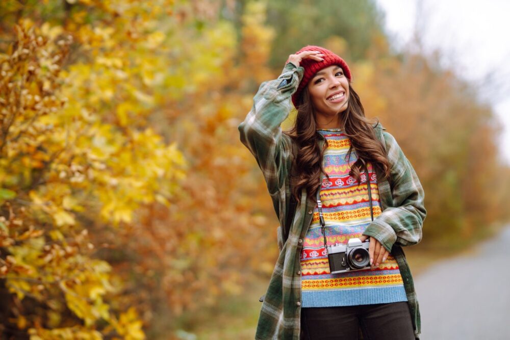 Falleg ung kona er mynduð með retro myndavél. Hvíld, afslöppun, ferðalög, lífsstíll.